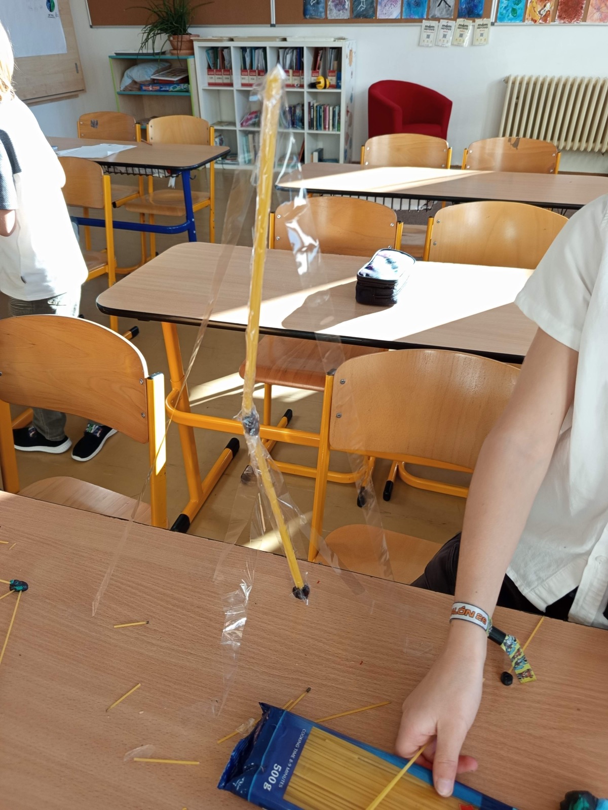 Vysoká tenká věž ze špaget zpevněná průhlednou páskou